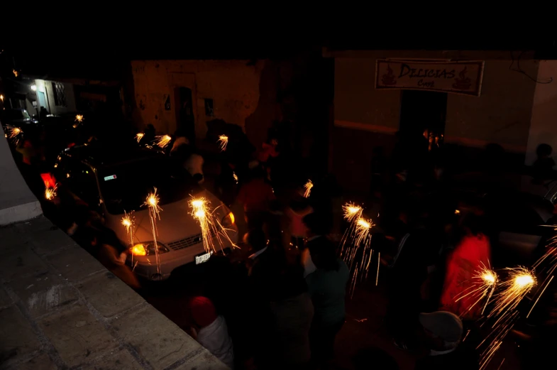 several people standing around a van with lit candles