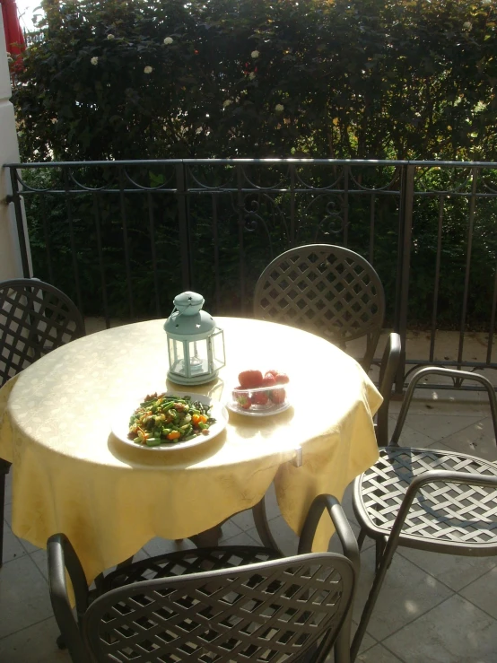 a small patio table with a lit candle and plate of food on it