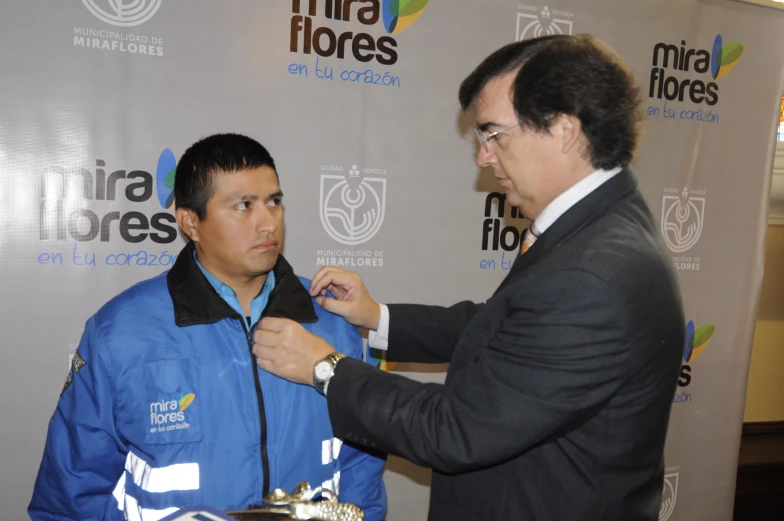 a man helping another man get ready for a suit