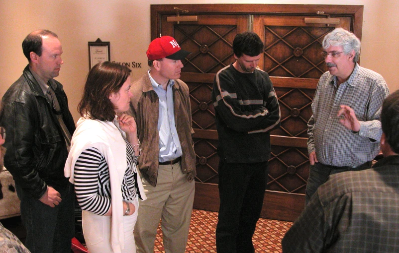 several people are standing in a room with wooden doors