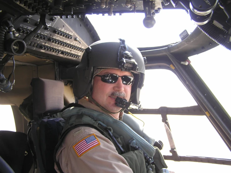 a pilot sits in a helicopter with a flag on the cockpit