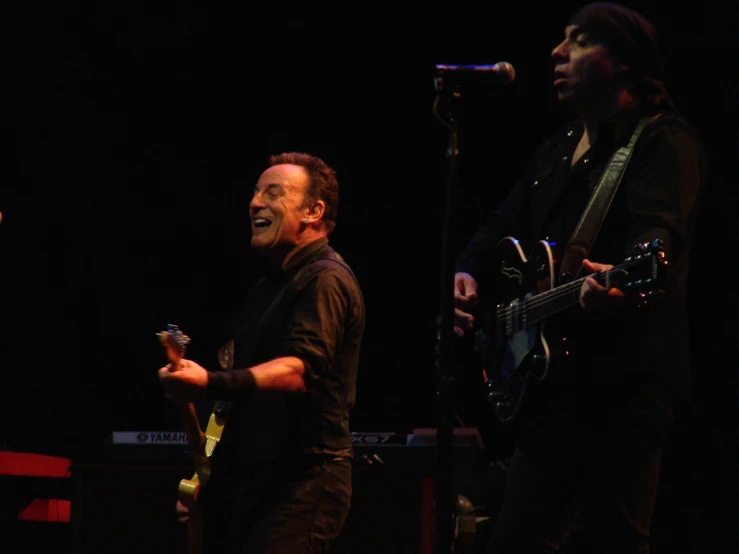 two people standing in front of microphones while they play