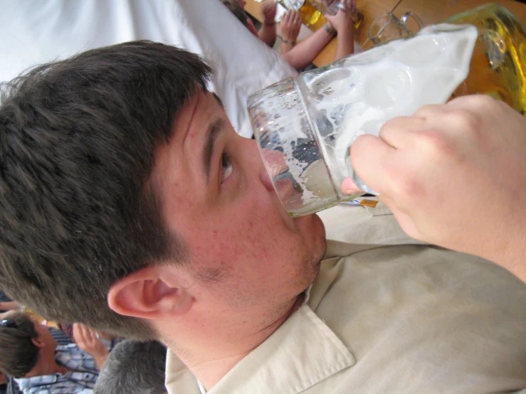 a man in a white shirt drinking beer from a wine glass