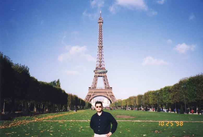 a man in a blue shirt standing in front of the eiffel tower