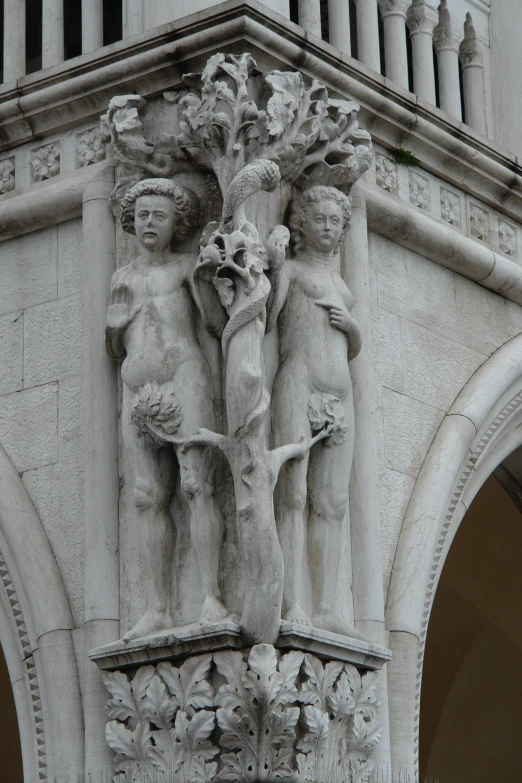 two statues sit next to each other on the front of a building