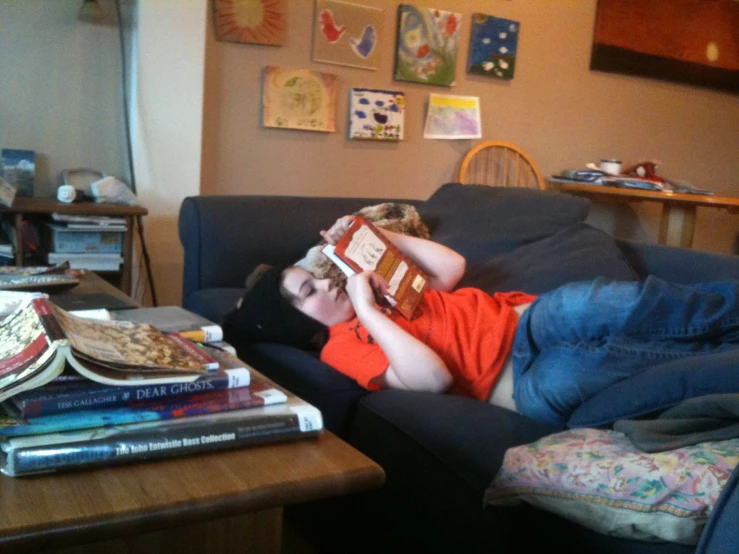 a boy is lying on the couch reading a book