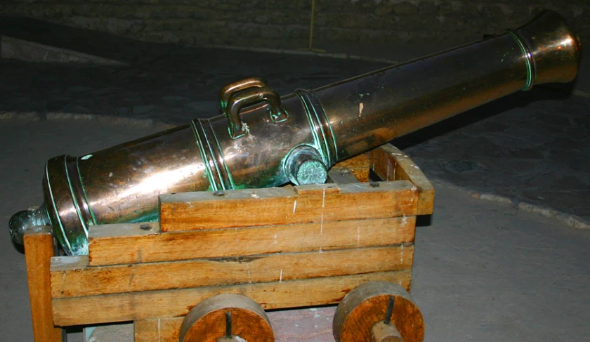 an antique metal cannon on wheels on top of a wooden cart