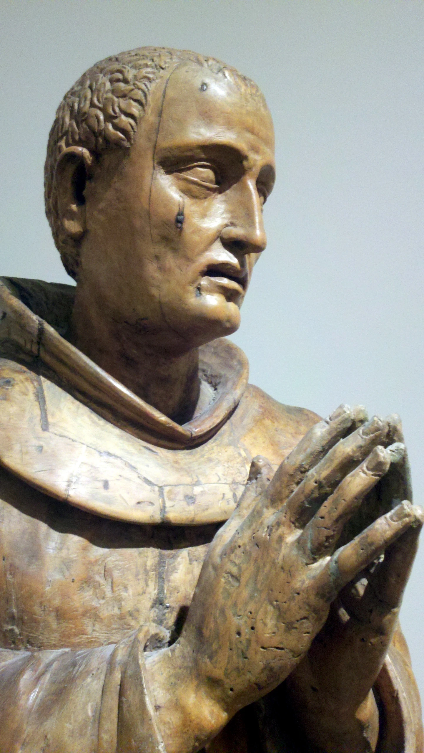 statue of a man wearing a cross with one hand