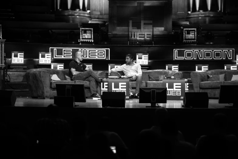 a black and white po of two people sitting in front of an audience