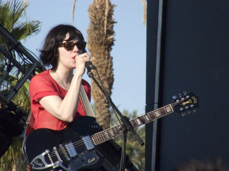 a person with a guitar sings into a microphone