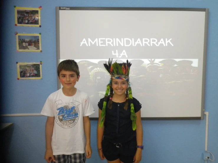 two children with hair pieces on their head posing in front of a whiteboard