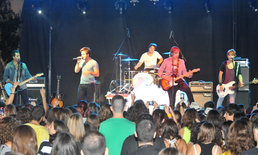 a band on stage with large audience and onlookers watching