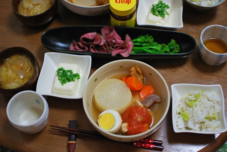 a wooden table filled with bowls and plates of food