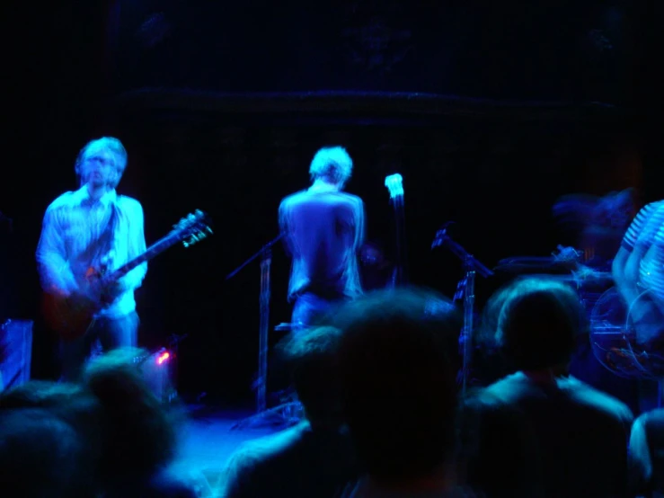 a band performing on stage with people watching