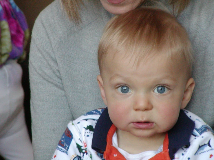 a young child in a sweater has a red bib on