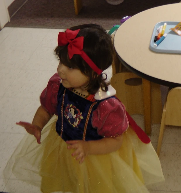 a little girl in a dress near a table