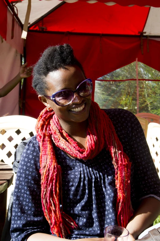 a woman is smiling and wearing shades and a red scarf