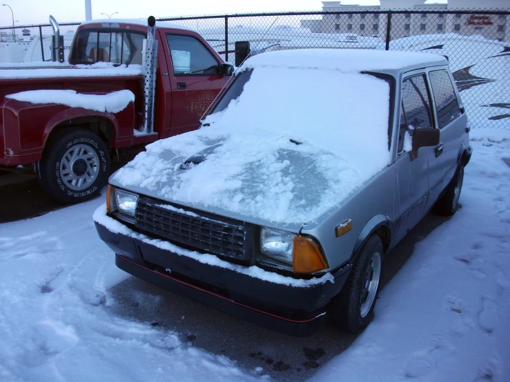 a car covered in snow next to a tow truck