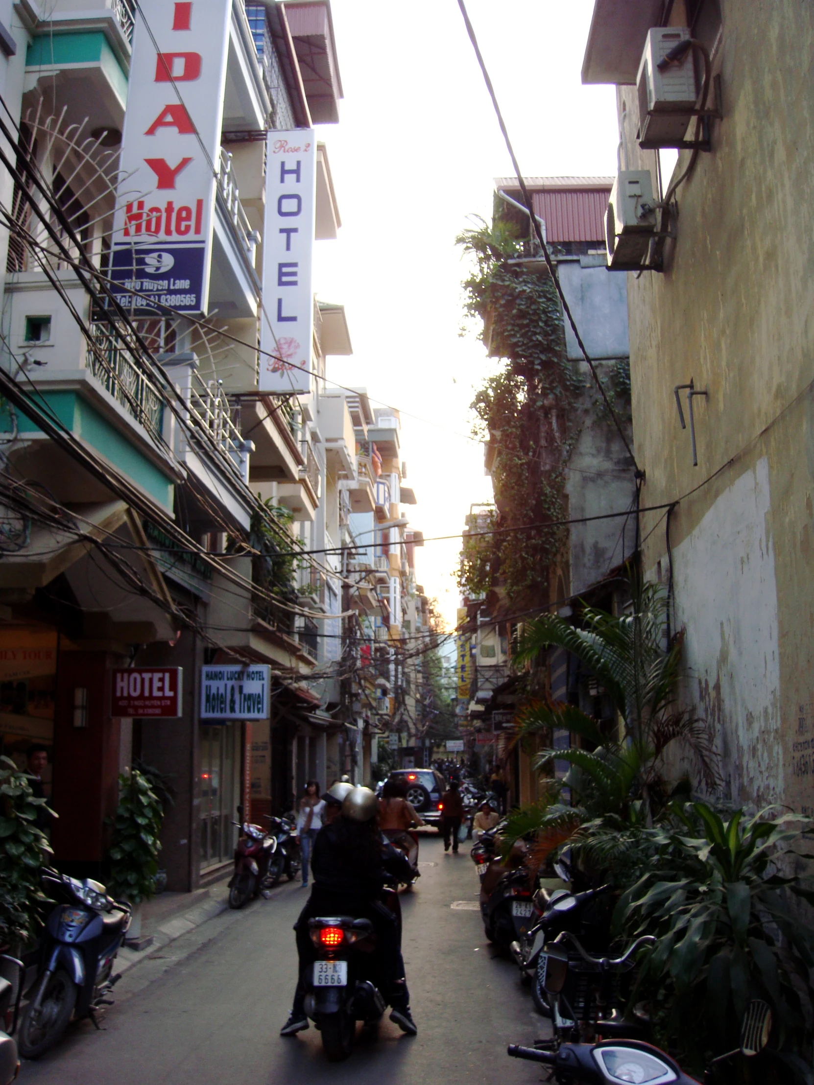 a man on a motorcycle driving down an alley with motels on either side