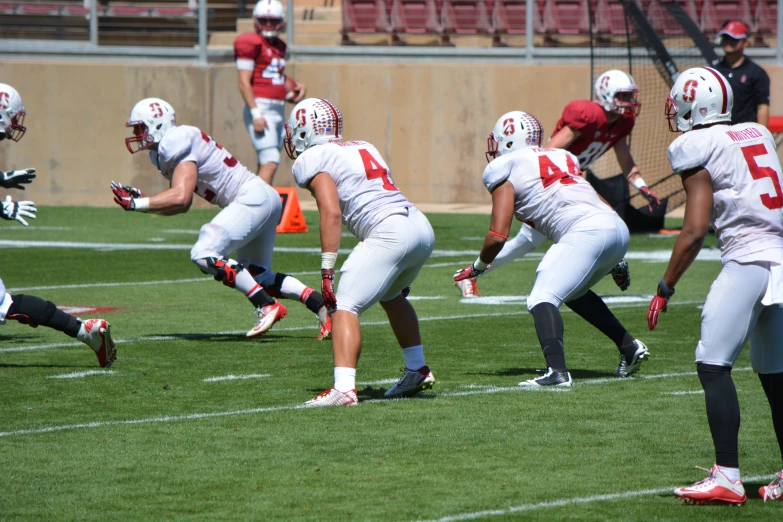 a football player lunges for a ball while another team tries to block him