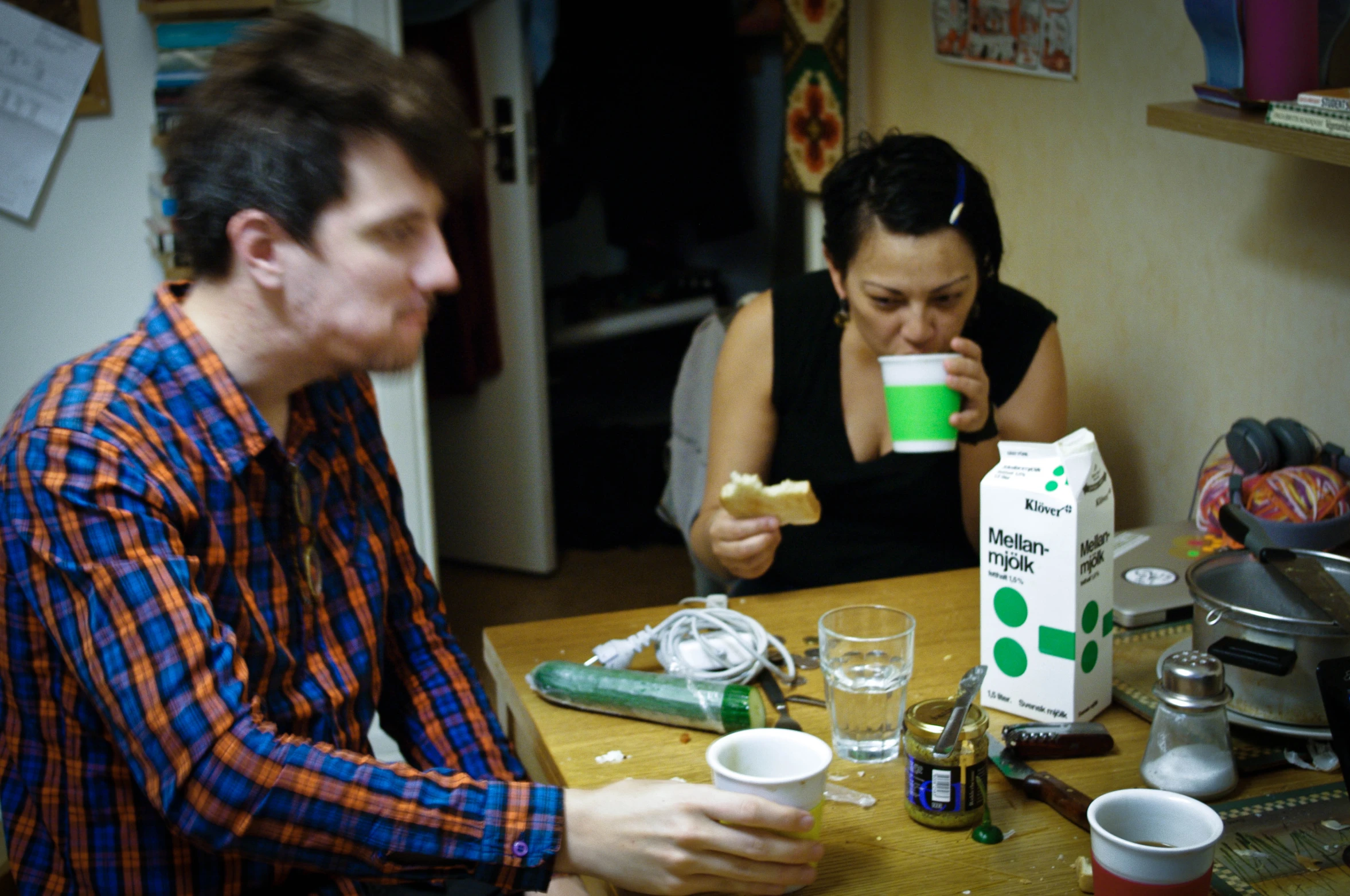 a man and woman sit at a table drinking from paper cups