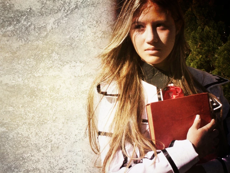 a woman with long, blonde hair holds a binder and book