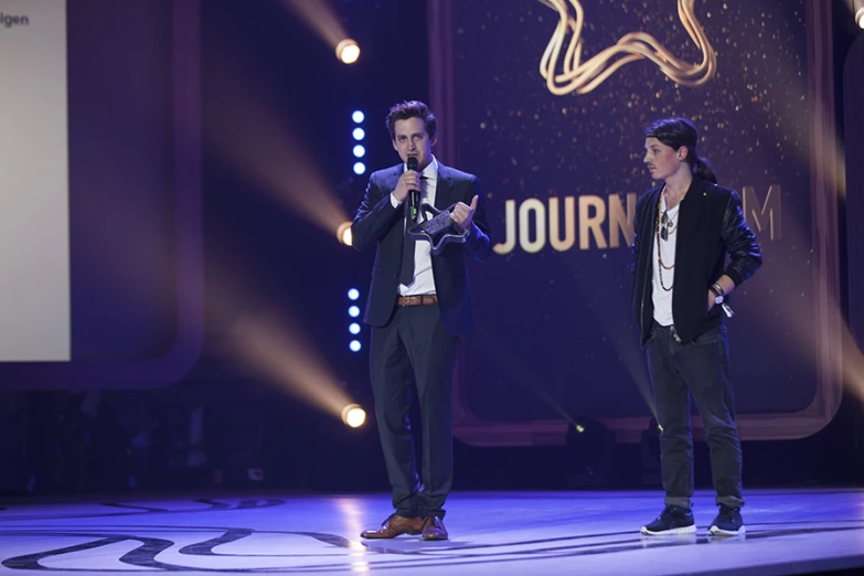 two men singing on stage and a screen in the background