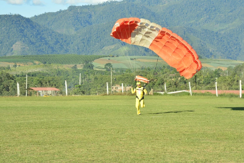 a person on grass holding a kite with mountains in the background