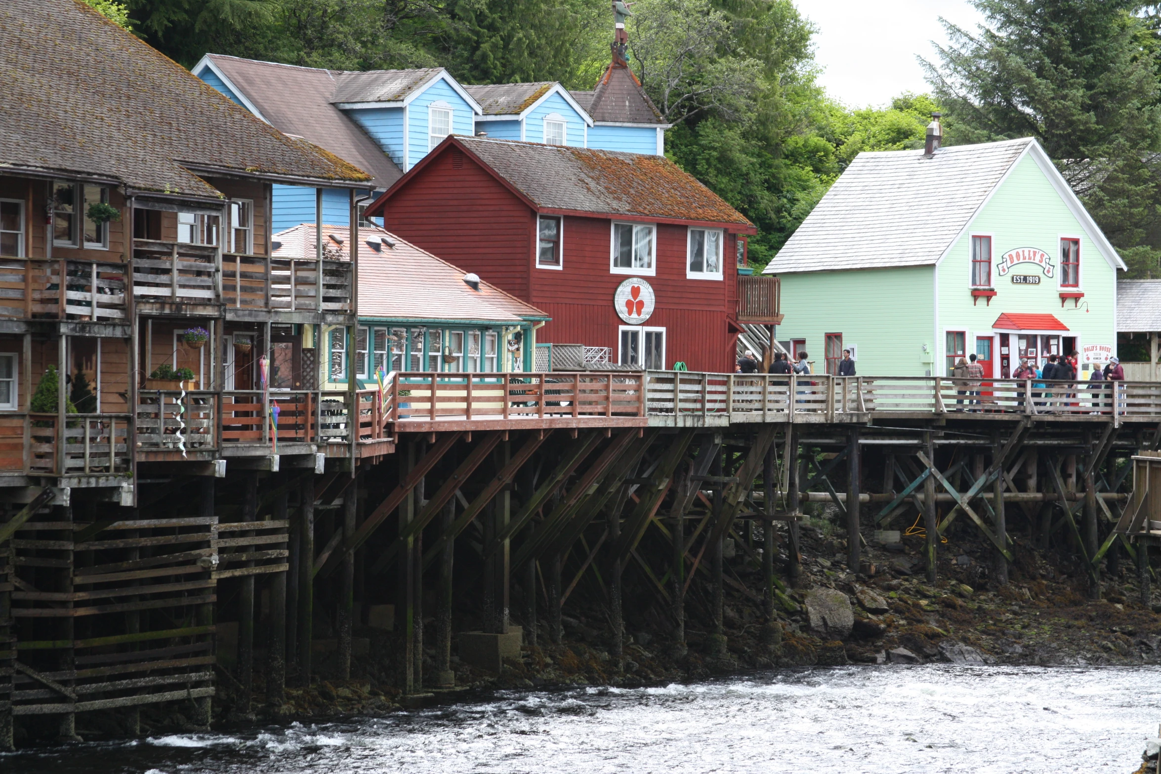 a large old - fashioned wooden pier stretches over a stream