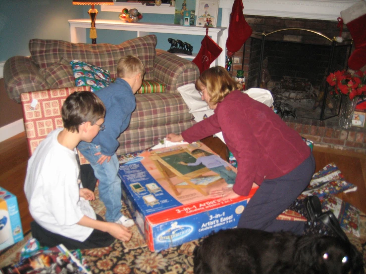 a woman and two children sitting on the floor with christmas presents