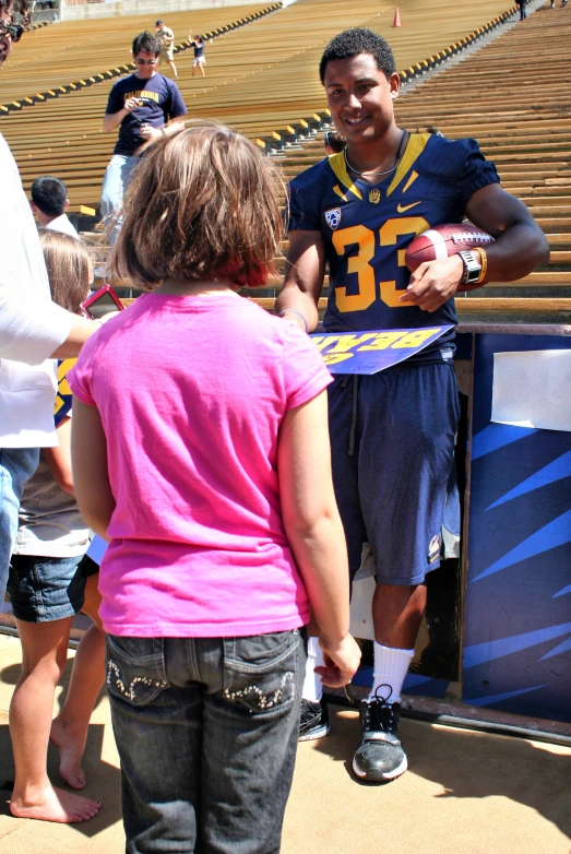 an excited child with a football uniform and a jersey at the football game