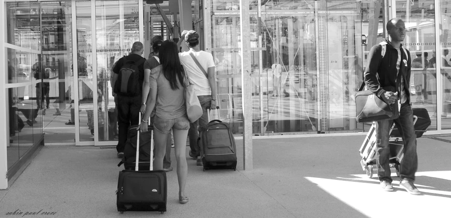 people with luggage walking towards the entrance of a store