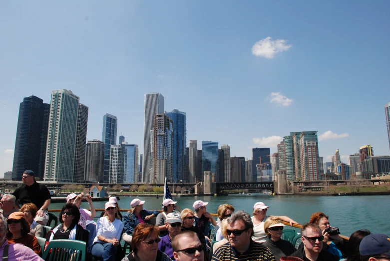 a large group of people sitting on a boat watching a large city