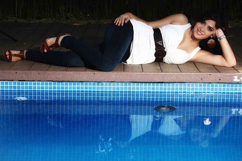 a woman laying next to a swimming pool