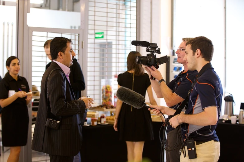 an attractive woman with cameras talking to two men