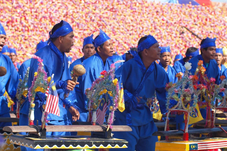 several men dressed in blue, performing an instrument procession