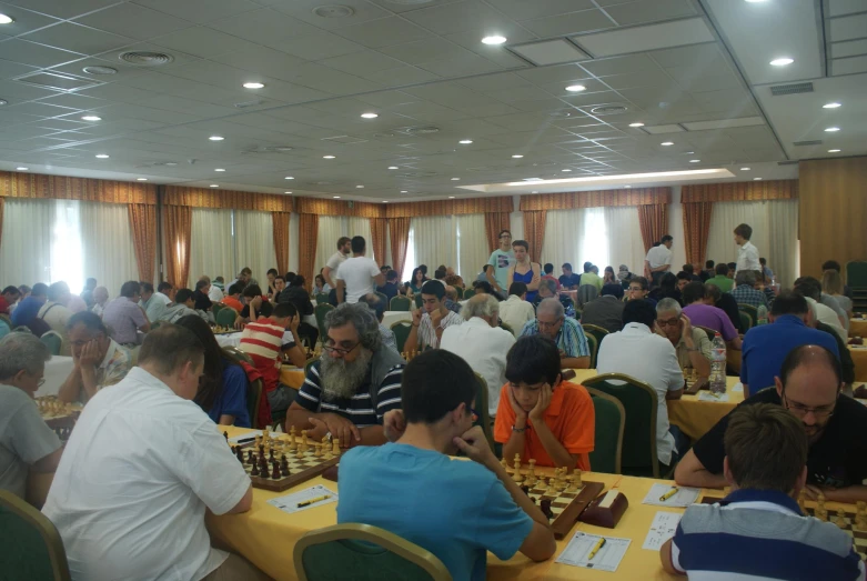 a large room filled with lots of people playing chess