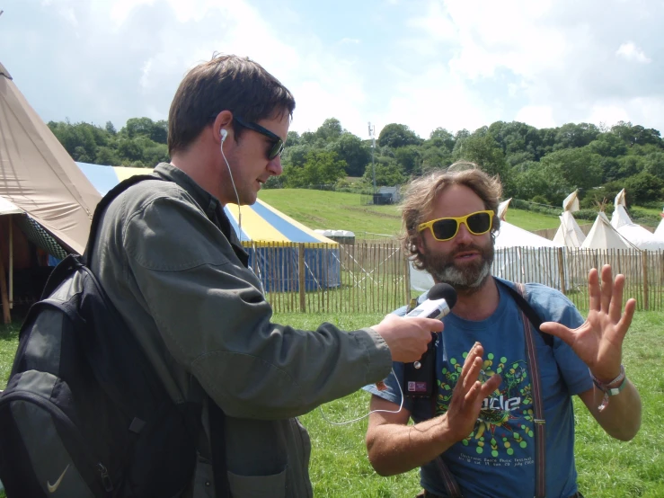 a man with a backpack wearing headphones talking to another man