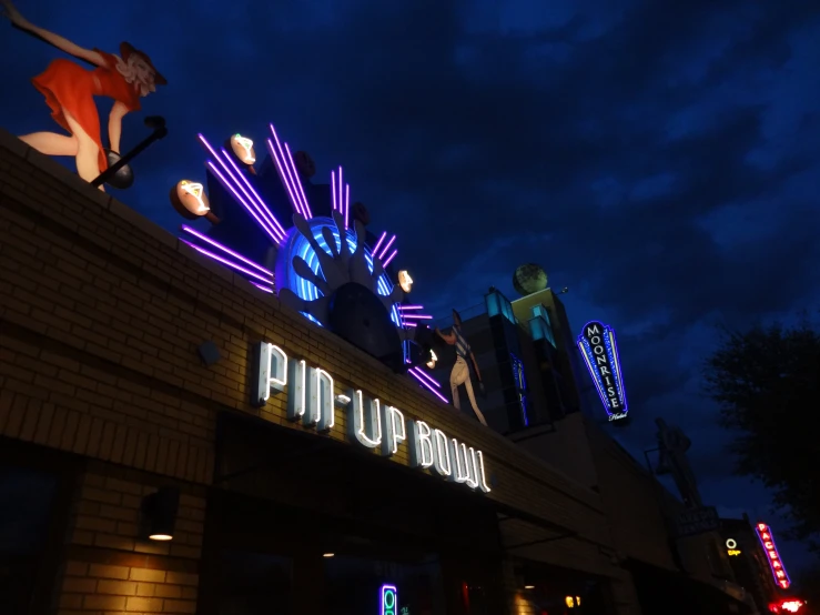 a dark night shows an illuminated ferris wheel and sign