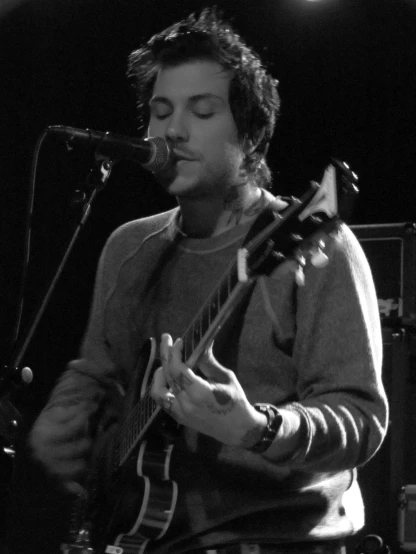 a young man is playing the guitar in front of microphones