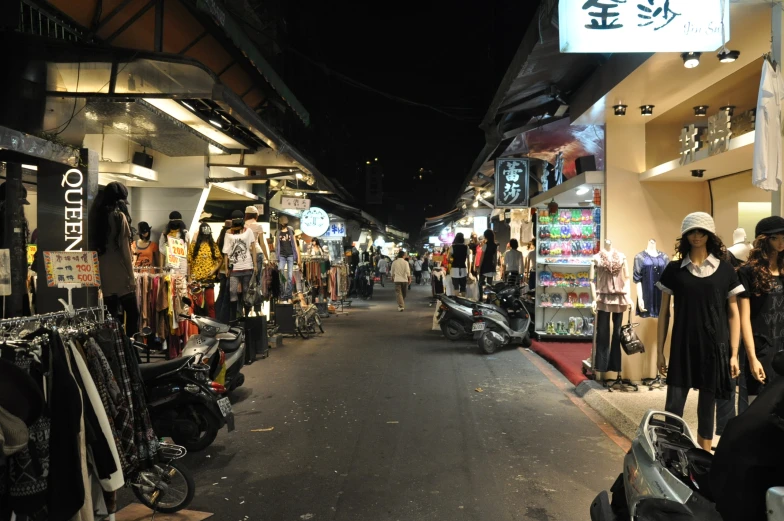 people are walking down the narrow street with shops and shops