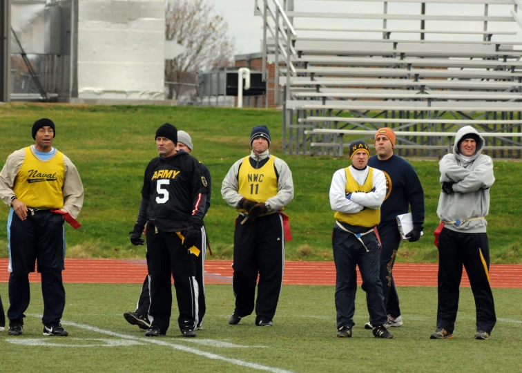 a group of men standing on top of a field wearing sports gear