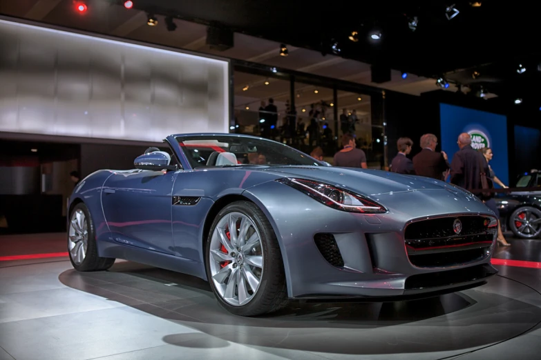 a silver sports car sits on display in a building