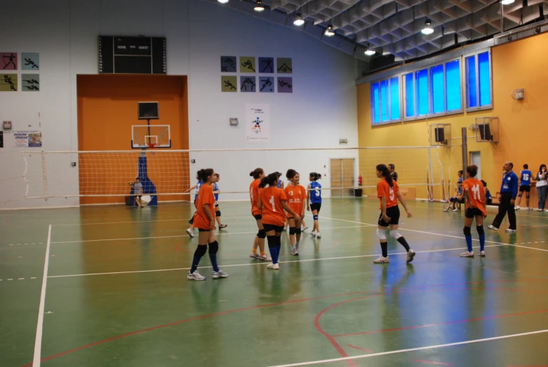 a bunch of girls standing in a gymnasium playing basketball