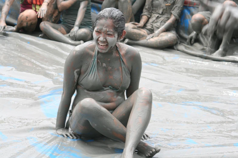 a woman covered in mud sits on the floor