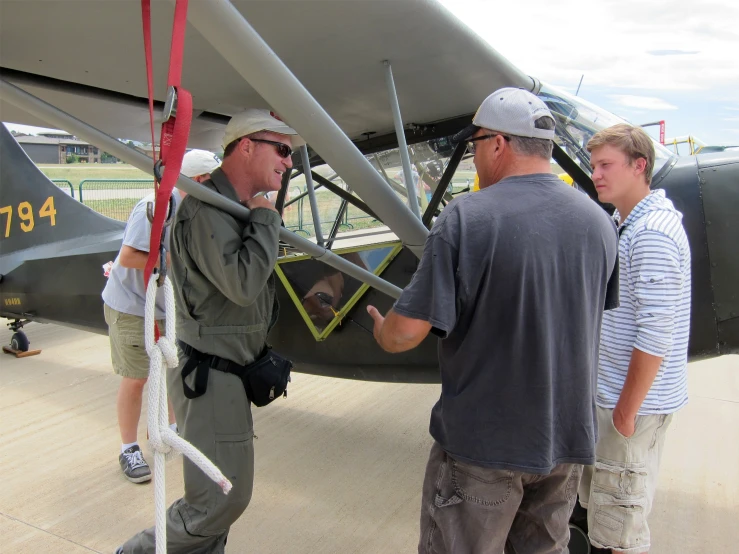 three men are gathered around a small prop plane