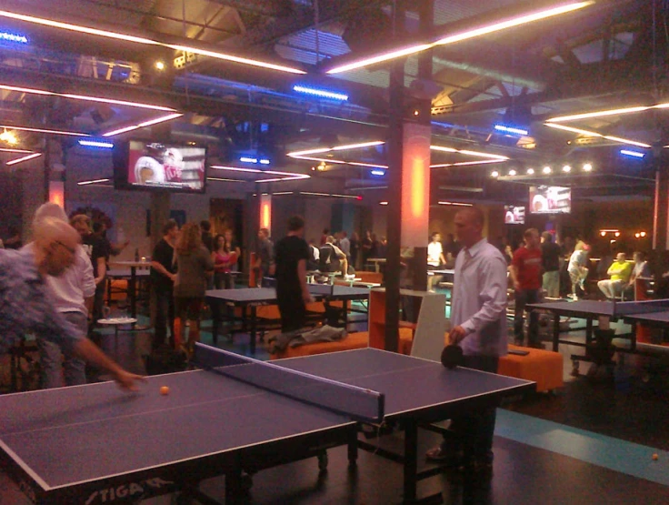 some people playing ping pong at an indoor game room