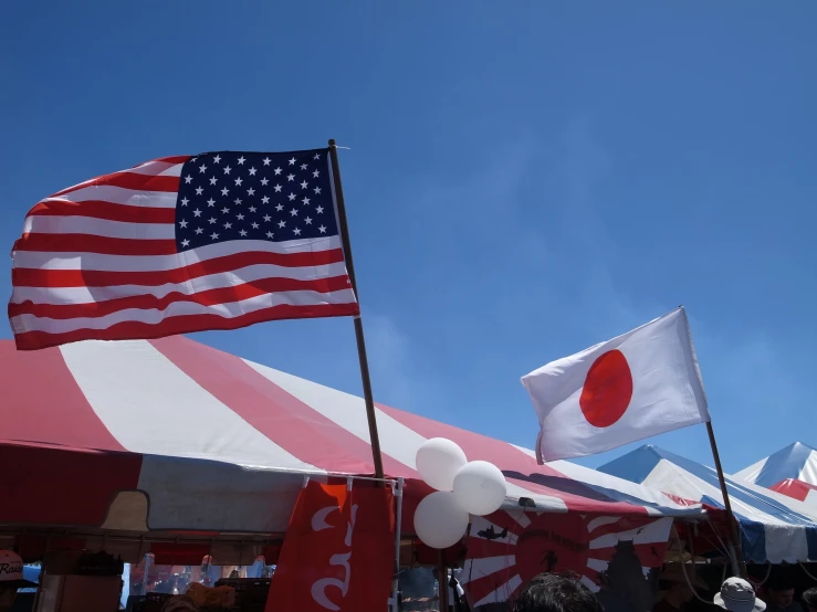 two flags blowing in the wind at an outdoor event