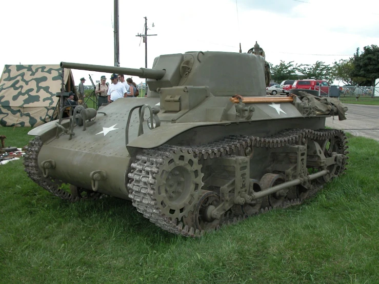 a tank on display in grassy area with many people around it