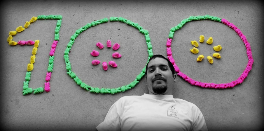 a man is standing next to a sign with balloons in the shape of a happy face